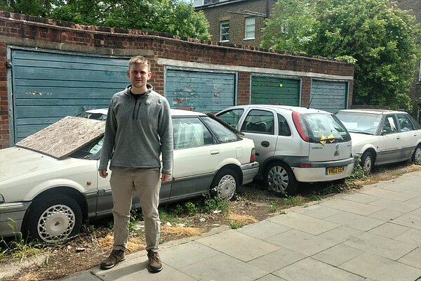 Cllr Adam Keenan standing next to abandoned cars on Windsor Road.