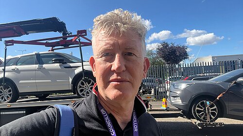 Cllr Jon Oxley taking a selfie next to a towed car.